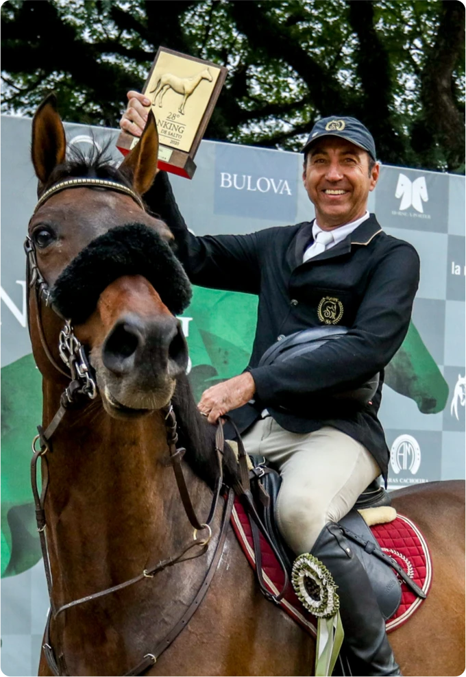 Sérgio Marins sorrindo a cavalo e segurando um troféu